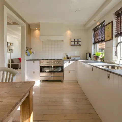 Cocina integral blanca con cubierta gris y mesa de madera